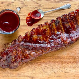 Low FODMAP Blackberry Maple BBQ Rib rack on wooden board with extra sauce