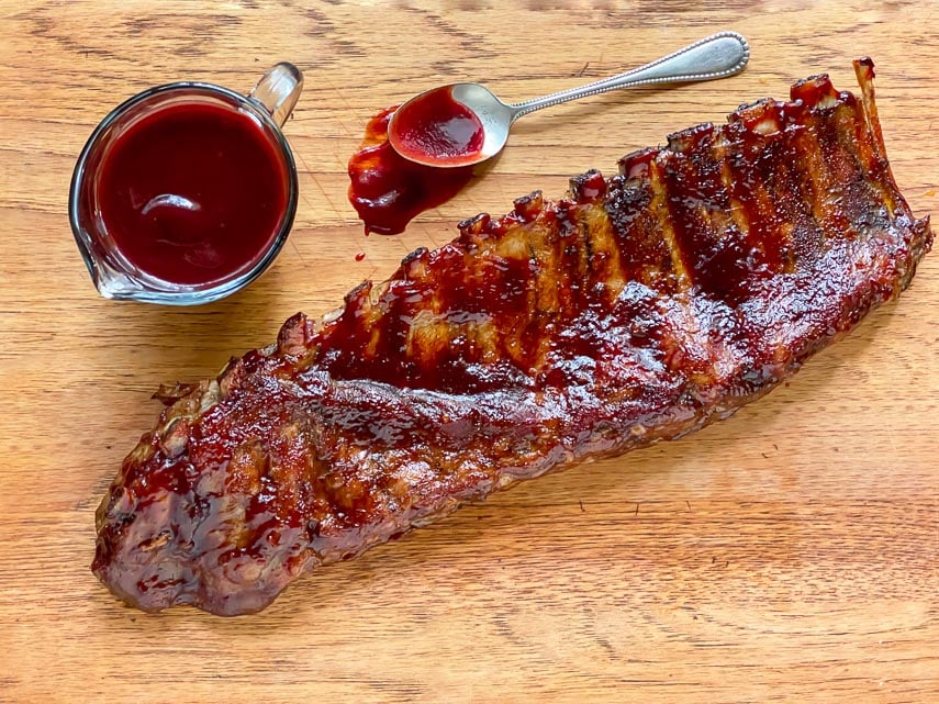 Low FODMAP Blackberry Maple BBQ Rib rack on wooden board with extra sauce