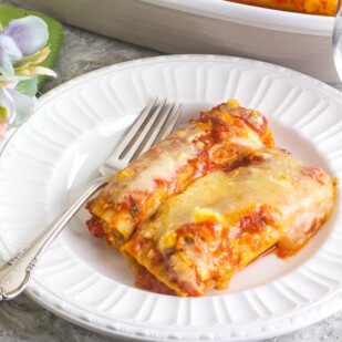 Low FODMAP Manicotti on a white plate with silver fork; green napkin