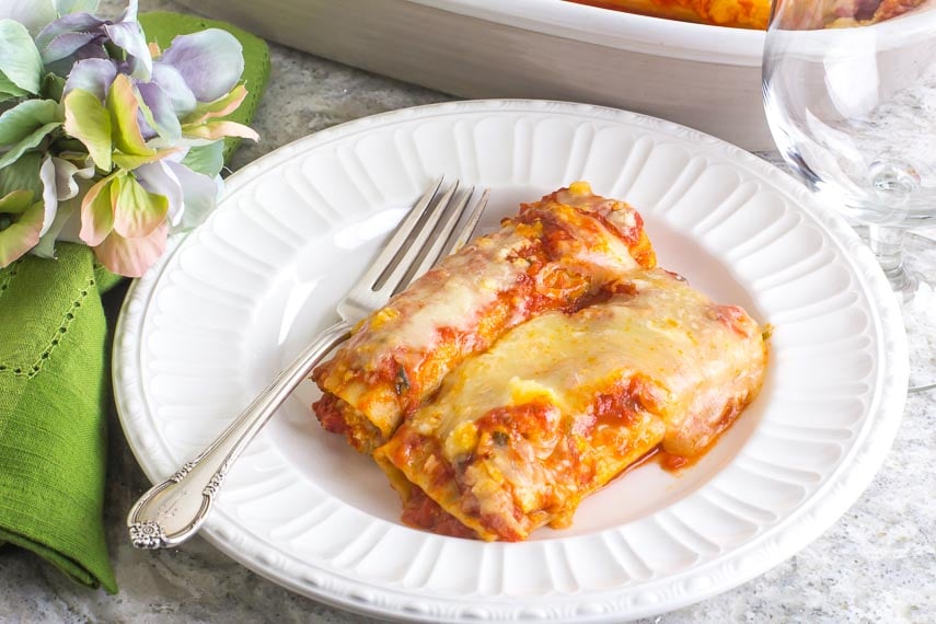 Low FODMAP Manicotti on a white plate with silver fork; green napkin