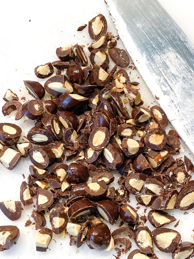 chopped chocolate covered almonds on a board with a chef's knife