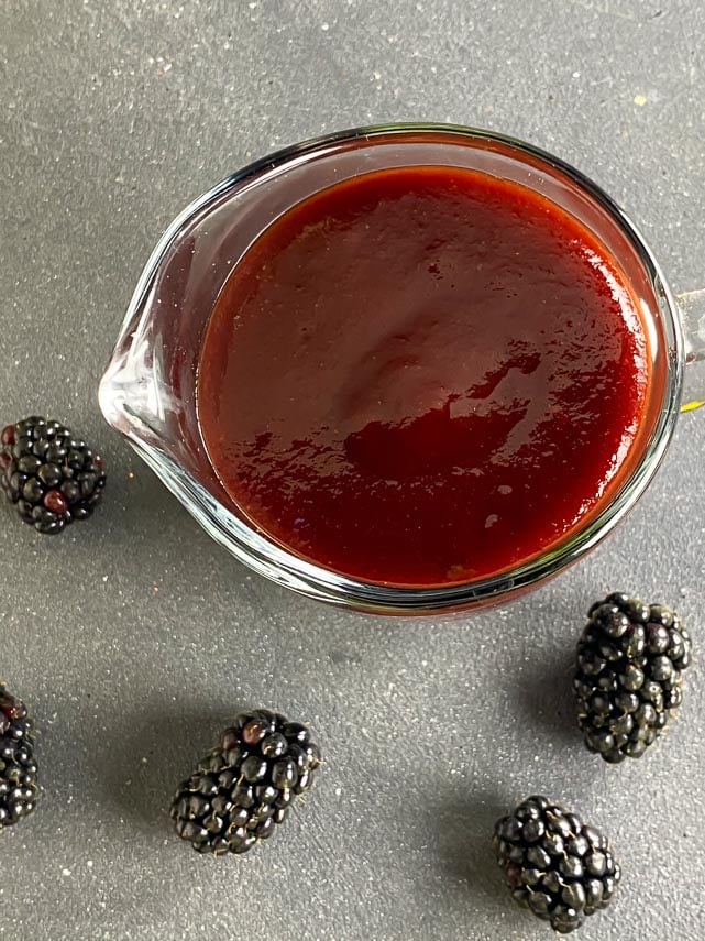 looking down into small pitcher of blackberry maple BBQ sauce on gray surface