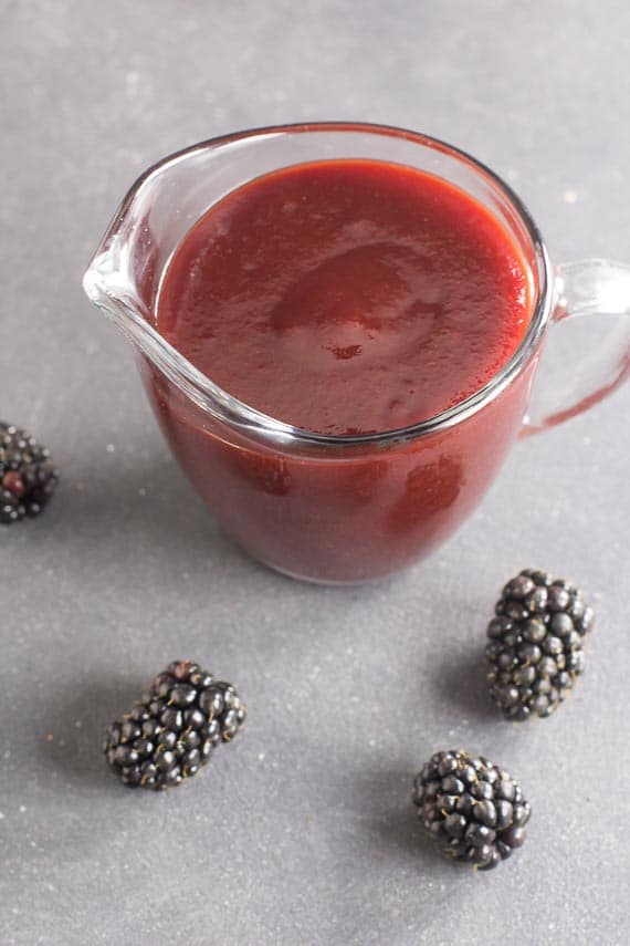 low FODMAP Blackberry Maple BBQ Sauce in clear pitcher, dark table