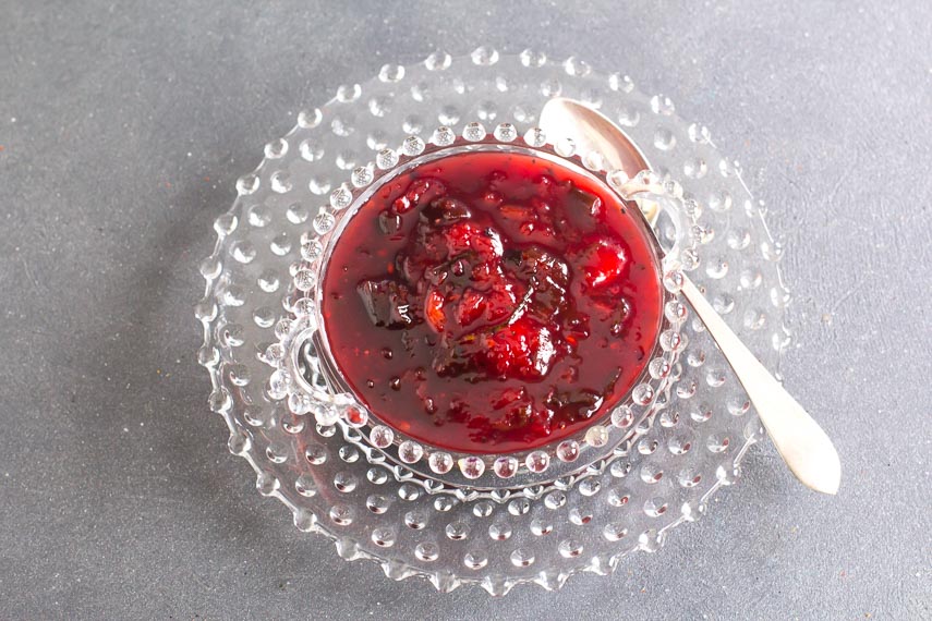 overhead shot of low FODMAP Blackberry and Peach Chutney in a decorative glass bowl with silver spoon