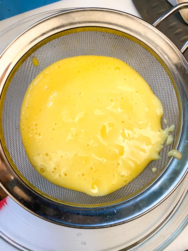 pouring liquified pineapple through a strainer