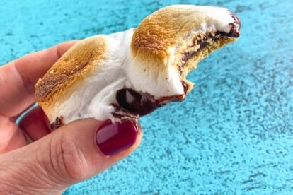 s'mores held in hand over aqua surface