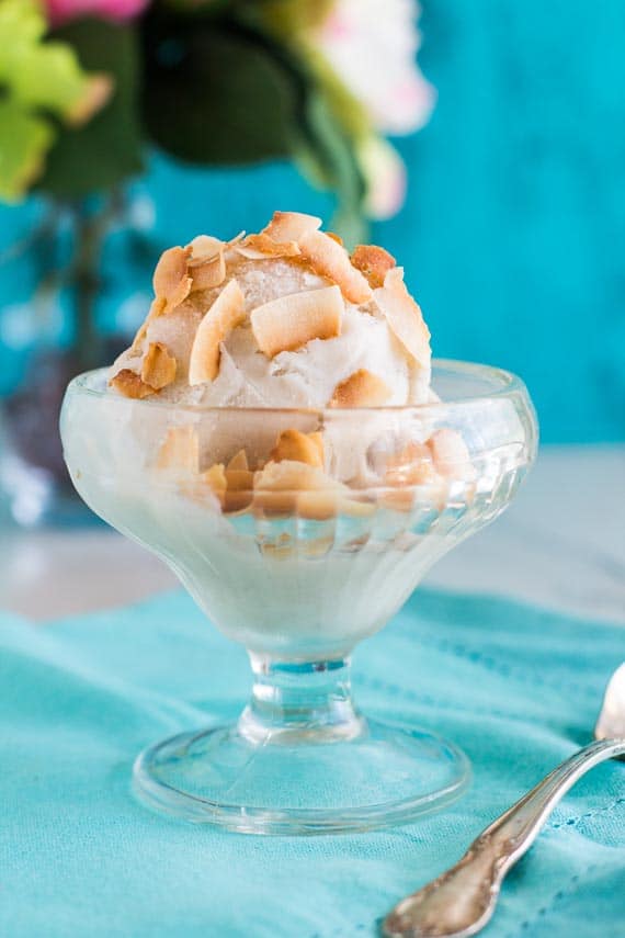 vertical image of low FODMAP banana coconut sorbet in clear dish with aqua napkin