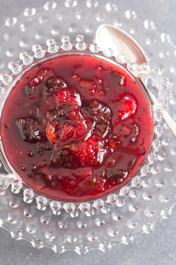 vertical shot of low FODMAP Blackberry and Peach Chutney in a decorative glass bowl with silver spoon