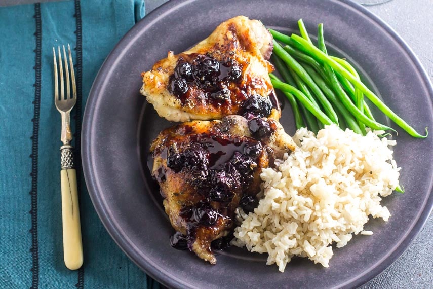 Low FODMAP Maple Balsamic Chicken With Roasted Blueberries on gray plate with rice and green beans; antique fork alongside