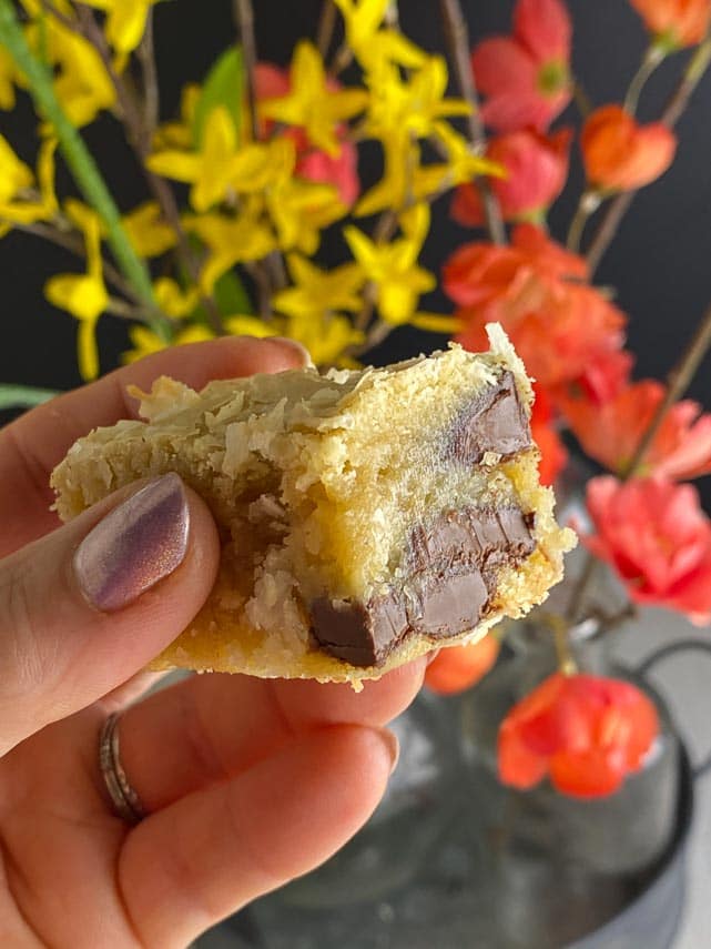cookie dough blondie held in hand in front of orange and yellow flowers