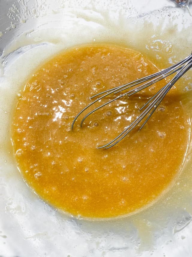 eggs completely incorporated into melted butter and brown sugar in glass bowl with whisk