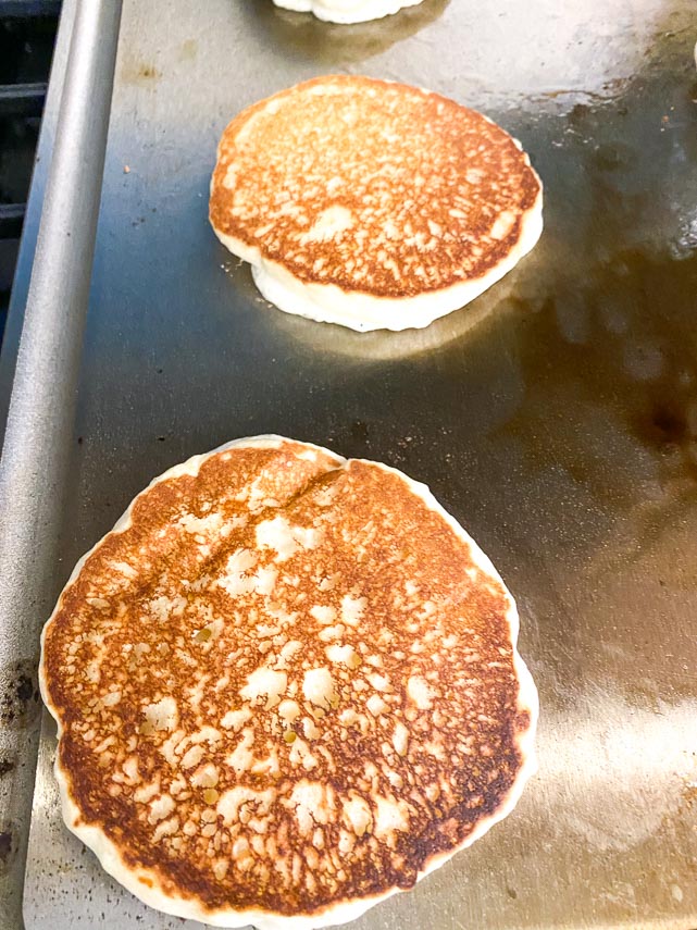 fluffy pancakes cooking on a griddle, closeup