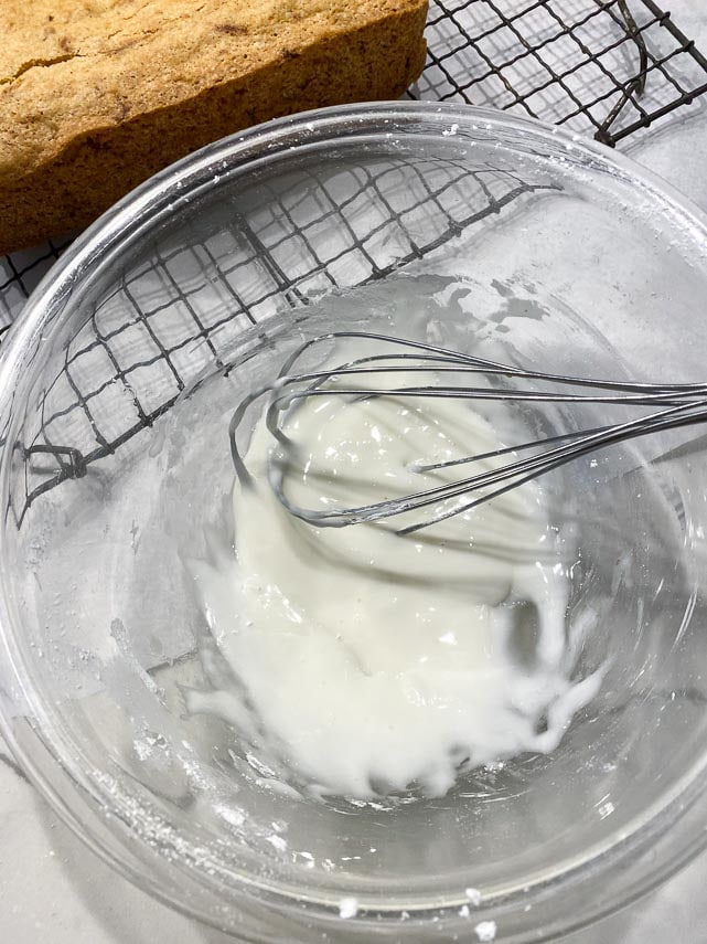 lemon glaze for quick bread being mixed in glass bowl with whisk