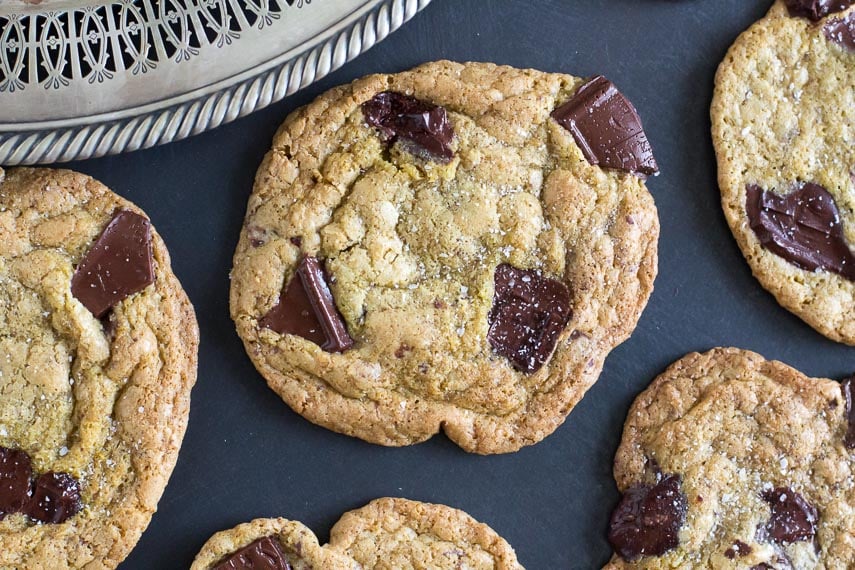 low FODMAP Salted Buckwheat Chocolate Chunk Cookies on a dark surface; silver tray showing in corner