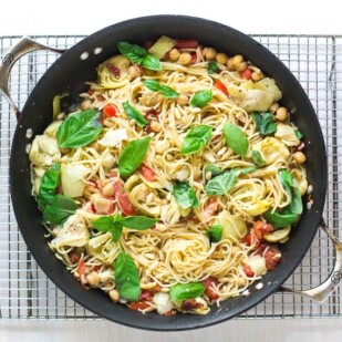 overhead image of pasta dish with chickpeas, tomatoes and artichokes in a pan on a cooling rack