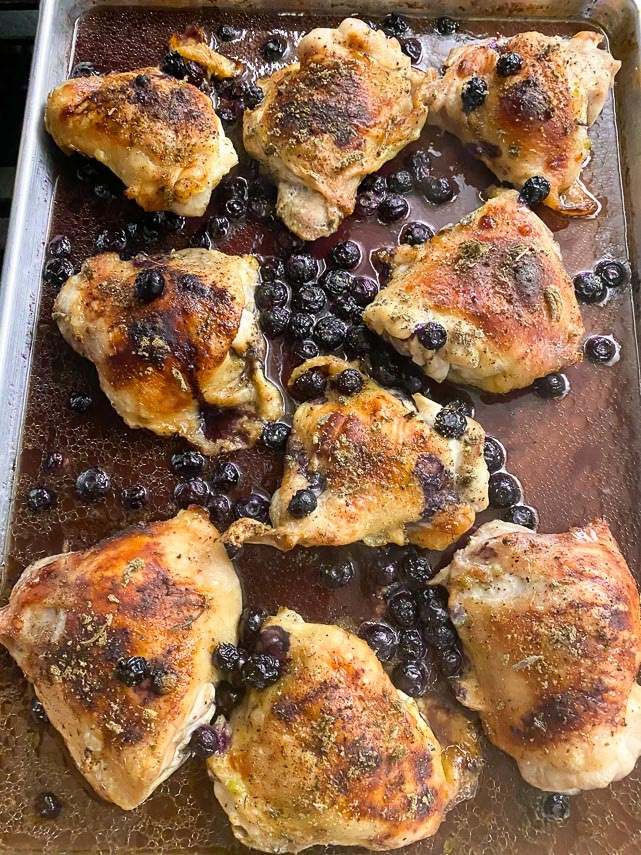 roasted chicken thighs with blueberries on pan showing crispy skin and roasted fruit