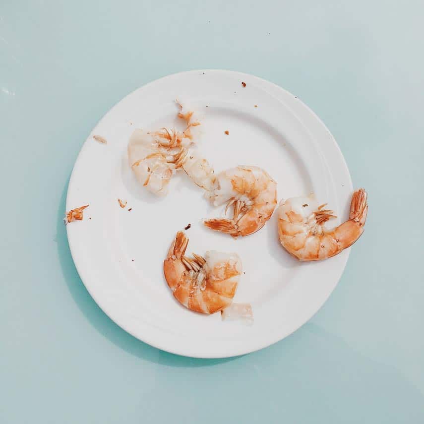 shell and tail on shrimp, some peeled, on a white plate
