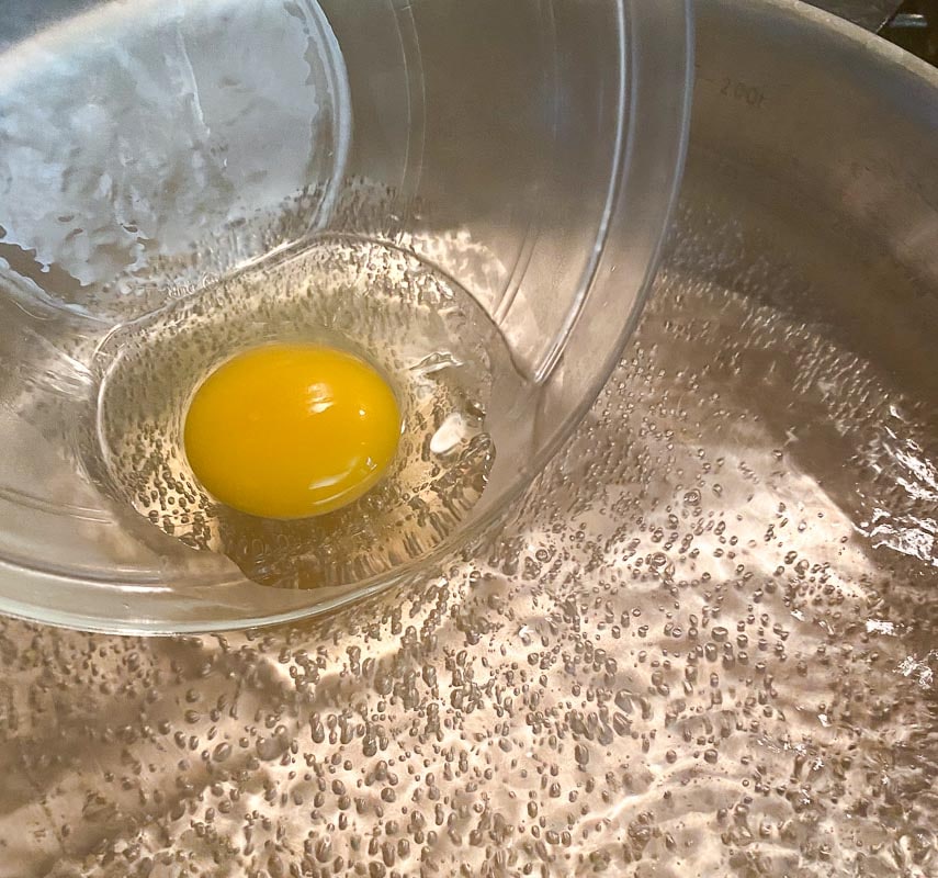 slipping egg into water for poaching