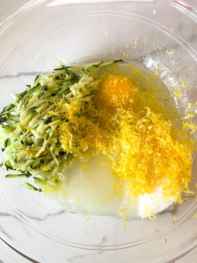 wet ingredients for lemon zucchini bread in glass bowl showing a lot of finely grated lemon zest
