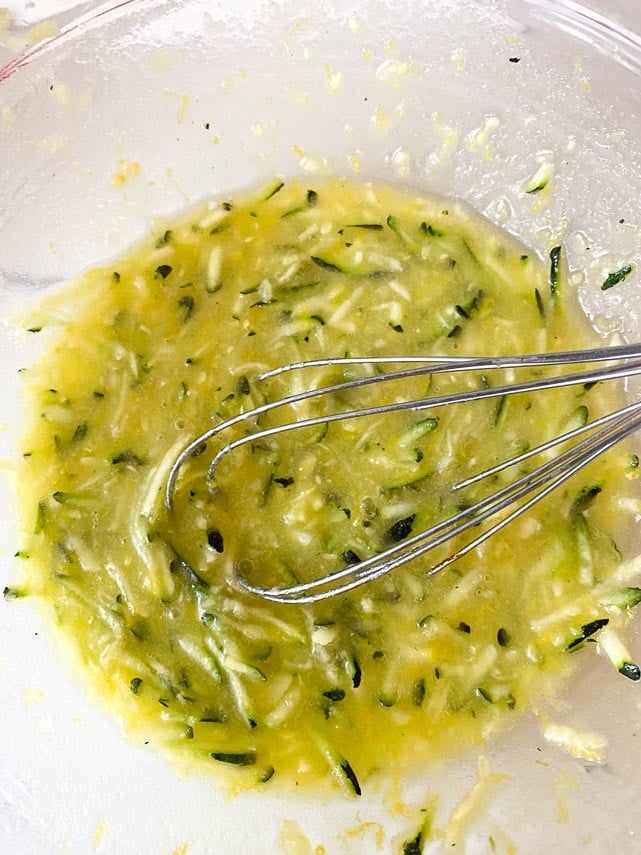 wet ingredients for lemon zucchini bread whisked together in glass bowl with whisk