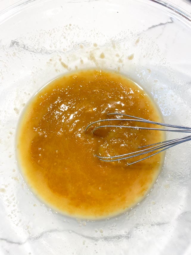 whisking brown sugar into melted butter in clear glass bowl