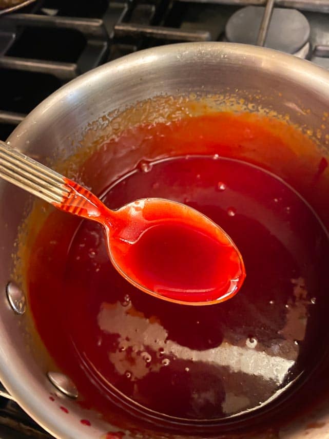 bloody red caramel sauce in spoon over pot made with red food coloring
