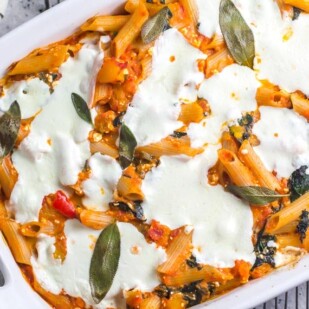 close overhead shot of baked pasta with roasted pumpkin, fresh mozzarella and sage in white baking pan on rack