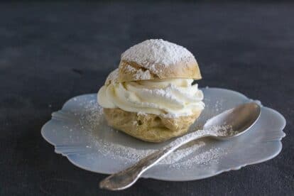 cream puff on white plate with spoon; dark background