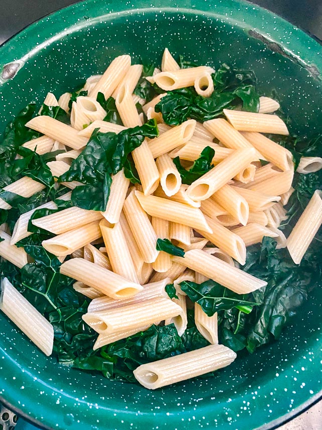 drained penne and kale, cooked, in green colander