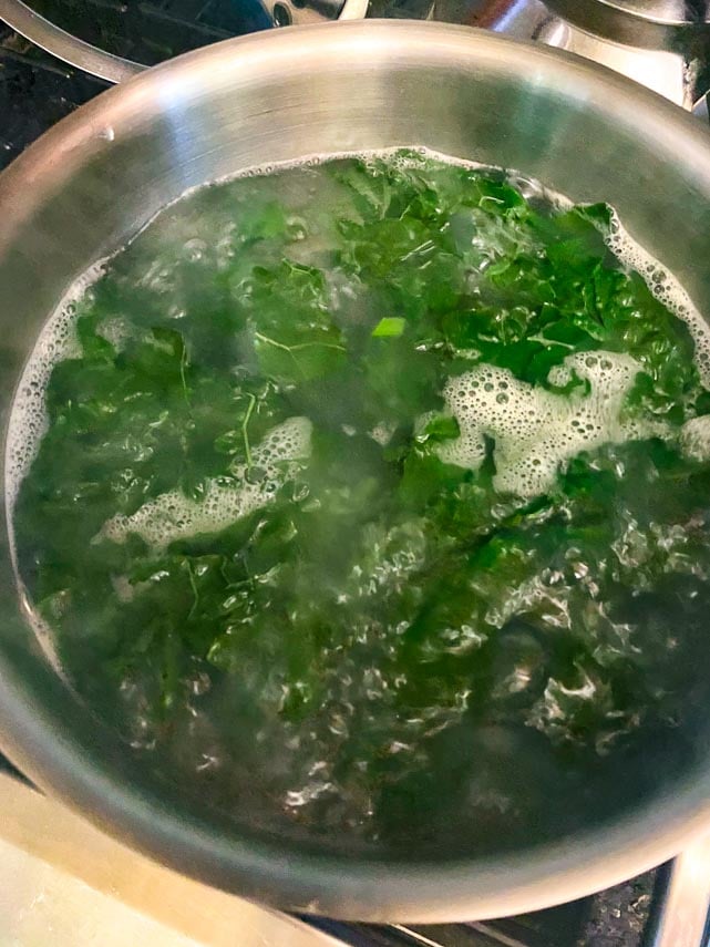kale added to pasta water cooking in pot on stove