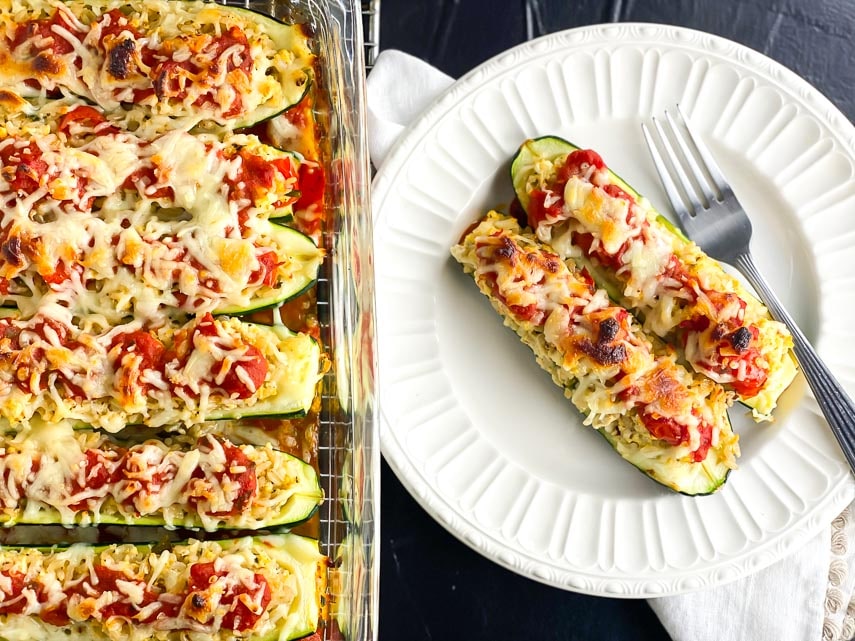 low FODMAP stuffed zucchini boats in glass baking dish and also alongside on white plate with fork