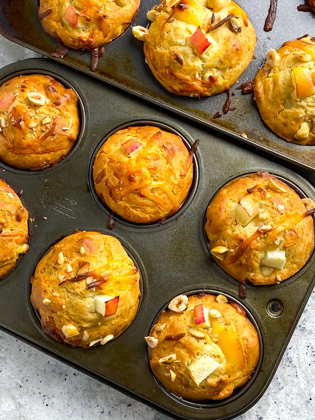 muffins tins, on the diagonal, holding smoked gouda apple muffins with hazelnuts