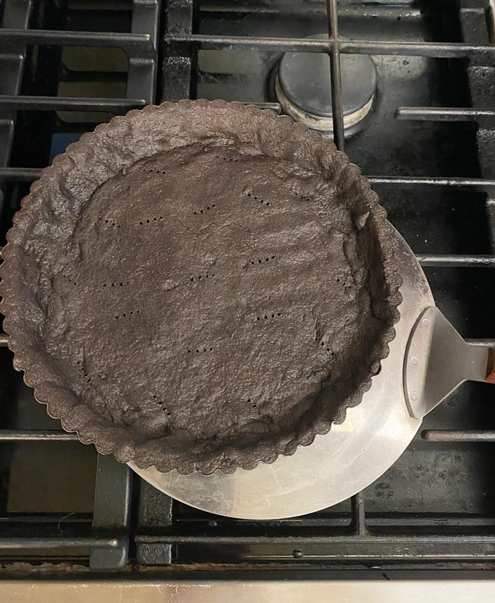 removing chocolate tart, par-baked, from oven with large round cake spatula