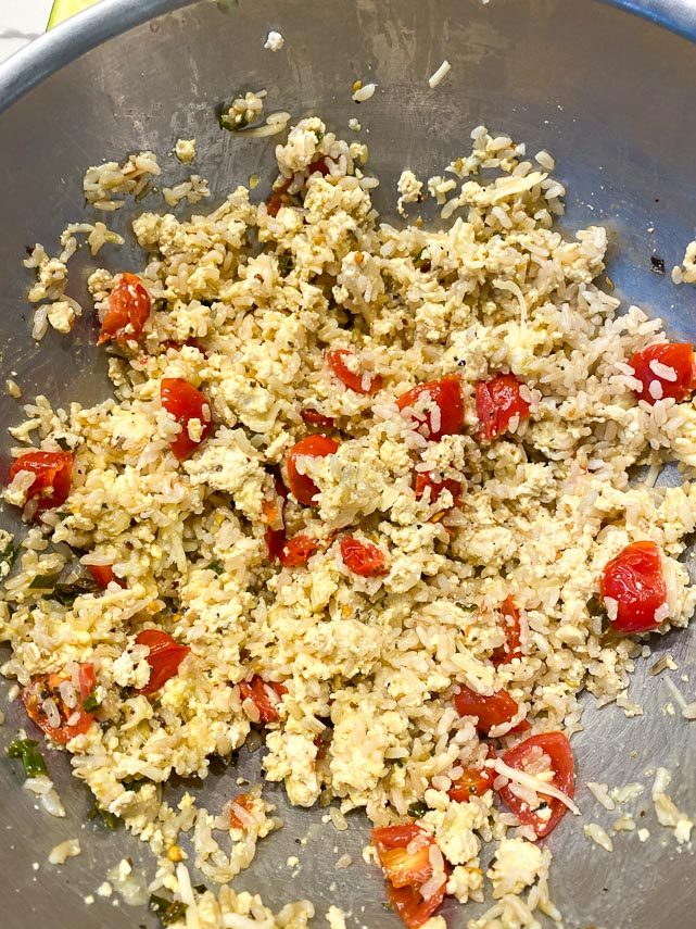 tofu, rice, cheese, tomatoes and egg mixed together in metal bowl - the makings of stuffing for zucchini boats
