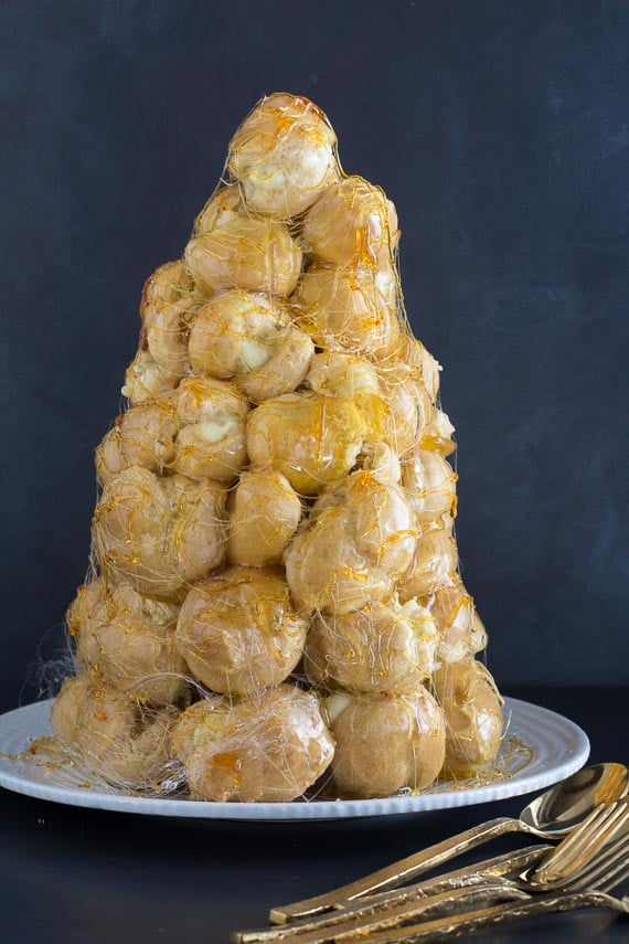 vertical image of croquembouche on white plate against dark background
