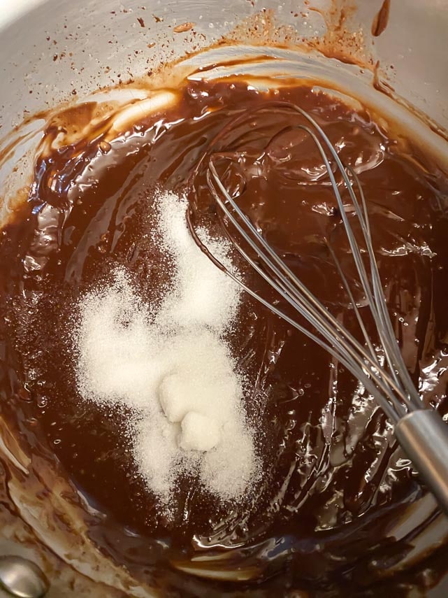 whisking sugar into chocolate tart filling in glass bowl