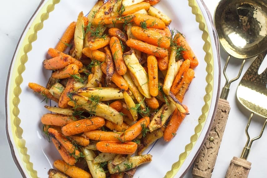 Low FODMAP Carrots & Parsnips with Dijon butter on oval platter with serving spoon and fork