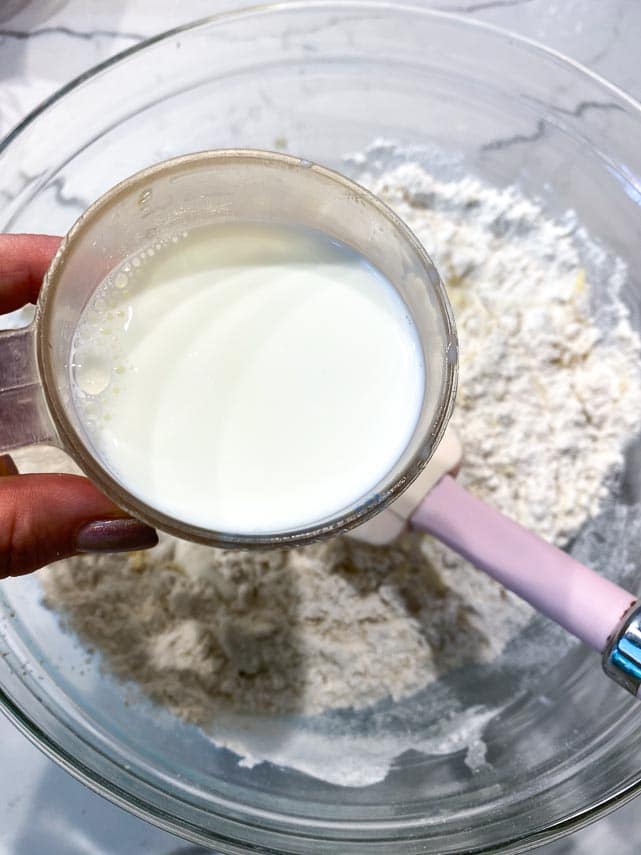 adding milk to cake batter in glass bowl