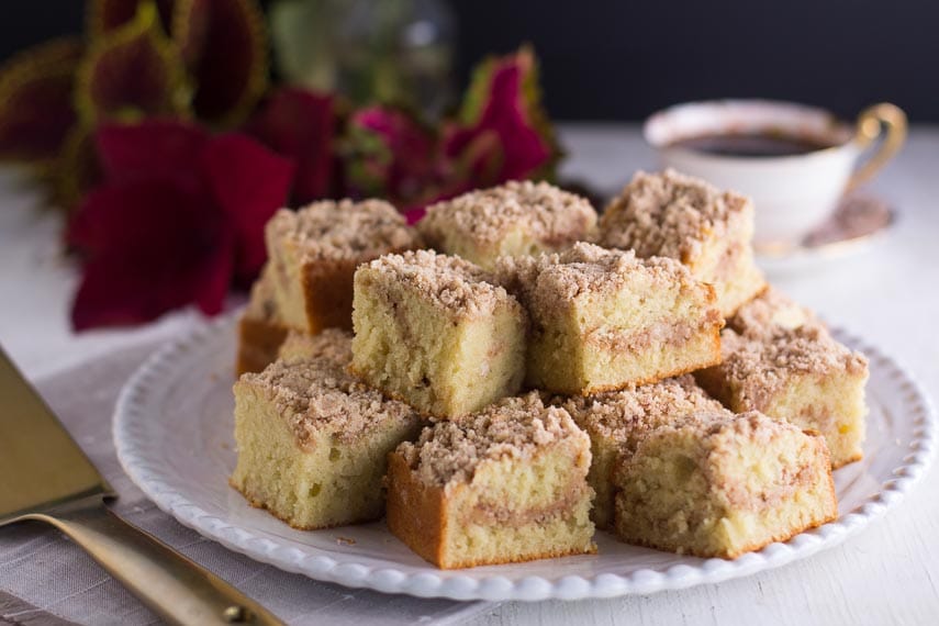 horizontal-image-of-low-FODMAP-one-bowl-streusel-coffee-cake-squares-on-white-plate-coffee-cup-in-background-gold-spatula-in-foreground