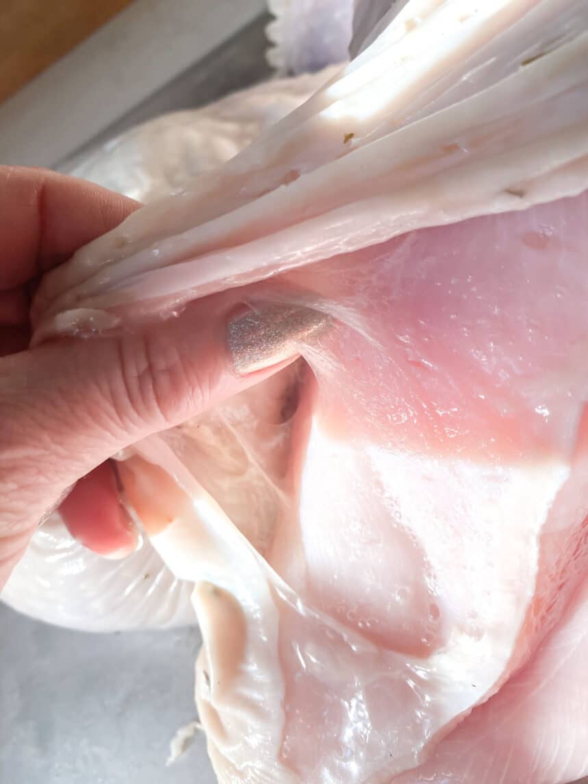 Using hands to separate skin from flesh on a turkey.