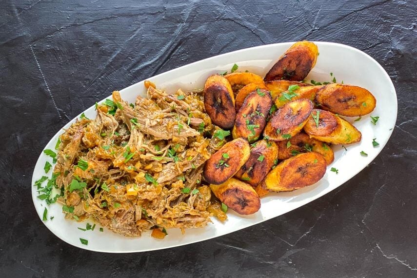 Low-FODMAP-Instant-Pot-Carribbean-Style-Pork-on-oval-whitev-plate-with-fried-plantains-dark-background