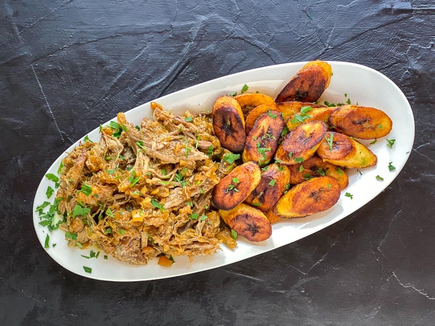 Low-FODMAP-Instant-Pot-Carribbean-Style-Pork-on-oval-whitev-plate-with-fried-plantains-dark-background