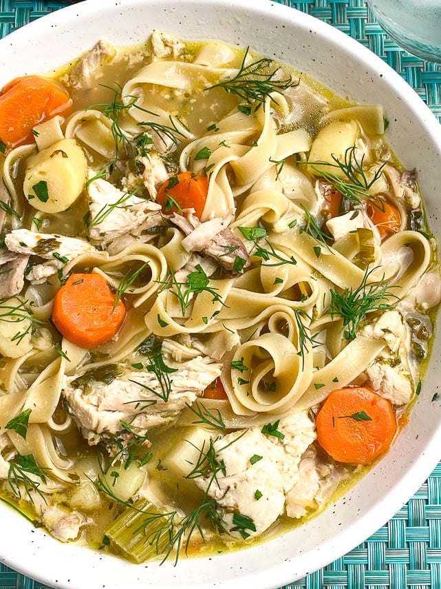 Low-FODMAP-nstant-Pot-Chicken-Noodle-Soup-with-Dill-in-white-bowl-on-aqua-placemat