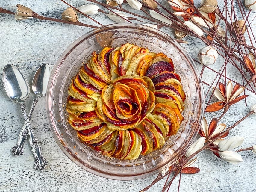 baked-root-vegetable-tian-in-glass-dish-on-white-painted-surface