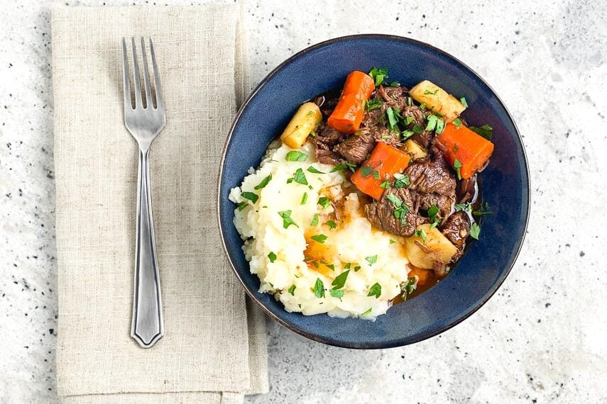 horizontal-overhead-image-of-Low-FODMAP-Instant-Pot-Beef-Stew-in-blue-bowl-on-gray-background