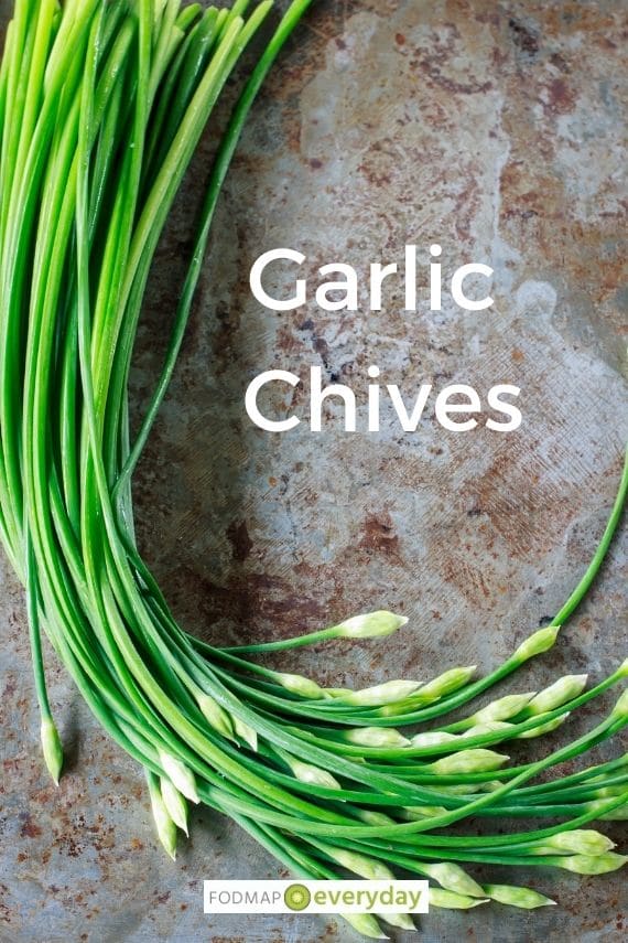 fresh garlic chives laying in a bunch on a stone surface