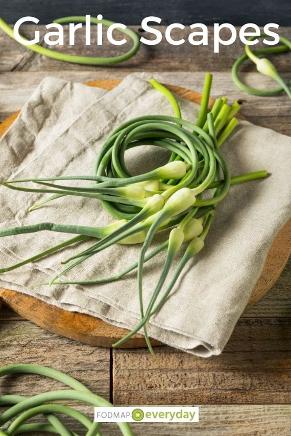 Fresh garlic scapes cut and gathered laying on a beige towel on a wooden board