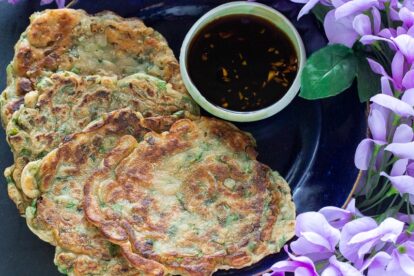 Low-FODMAP-scallion-pancakes-on-dark-plate-with-dark-background-with-dipping-sauce-and-purple-flowers-2AP