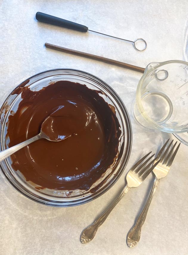 melted chocolate in glass bowl; candy dipping tools alongside
