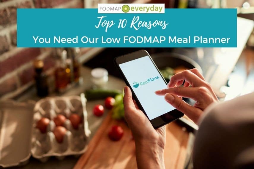 Top 10 Reasons you need our low fodmap meal planner. Image of woman holding her cell phone looking at her meal planner with kitchen counter and ingredients laid out below her hand. 